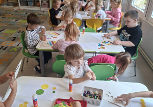 Dzieci tworzą obrazki przy stolikach z kropek