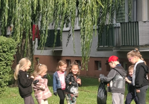 Dzieci na trawniku zbierają śmieci