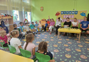 Dzieci siedzą wokół pracowników przedszkola