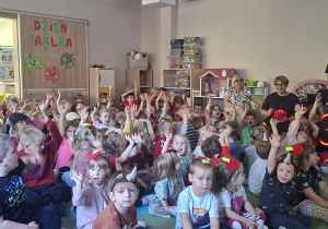 Dzieci słuchają ciekawostek o jabłku na dywanie