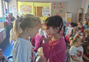 Dzieci biorą udział w konkurencji przenoszenia między głowami jabłka
