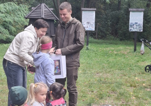 Dziewczynka wręcza podziękowanie p.leśniczemu