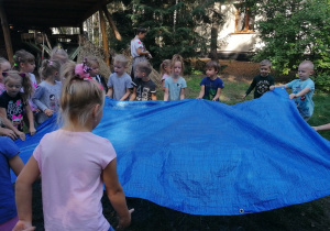 Dzieci rozkładają płachtę do młócenia ziaren
