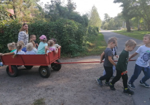 Chłopcy ciągną wóz z dziewczynkami