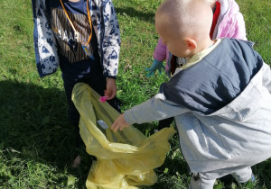 Chłopiec wrzuca śmieci do żółtego worka